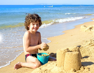 Cute baby boy playing with beach toys on tropical beach