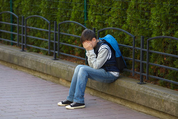 Schoolboy crying in the yard of the school