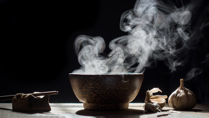 Bowl of hot soup with chopstick,spices on black background