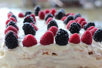 Cake with whipped white cream, fresh blueberries, blackberry and raspberry Close up.