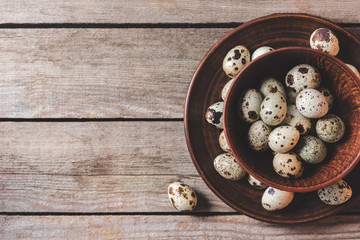 Obraz na płótnie Canvas top view of fresh raw organic quail eggs in bowls on wooden table