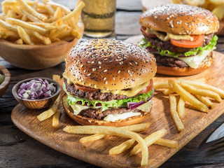 Hamburgers and French fries on the wooden tray.