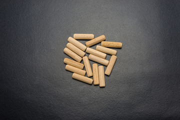 A lot of wooden pegs lying flat on a black background.