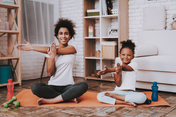 Mother and young daughter doing yoga together at home