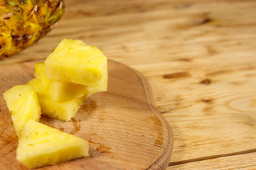 Pieces of pineapple on a cutting board on wooden table