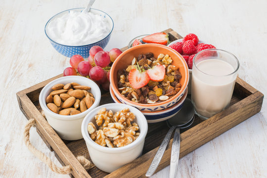 Paleo nut and fruit granola in a tray with fruits and berries, nut milk, coconut yogurt, copy space, selective focus