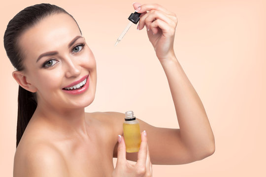 Closeup shot of cosmetic oil applying on young woman's face with pipette. Beauty therapy concept.