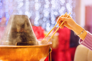 Chinese traditional hot pot with a hand with chopsticks in a restaurant