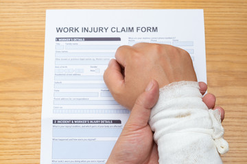 man with wrapped hand on top of a work injury claim form