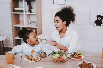 Mother Feeds Young Girl. Mom and Daughter Eat.