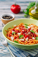 Spaghetti pasta with tomato sauce, mozzarella cheese and fresh basil leaves on white-blue vintage wooden background. Selective focus.