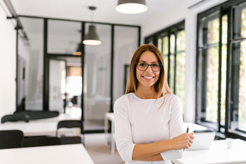 Portrait of smiling female entrepreneur in bright modern office.