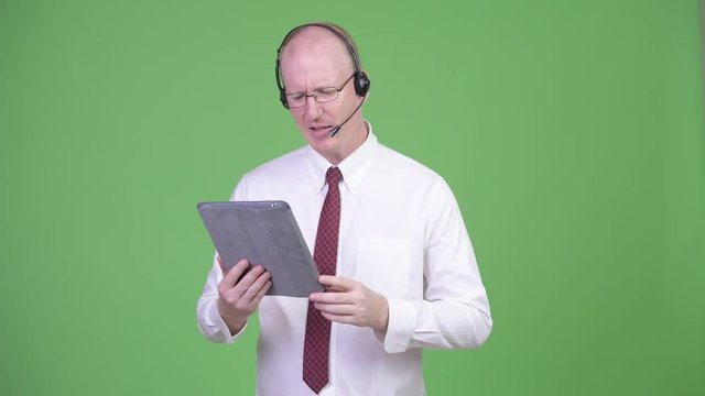 Happy mature bald businessman working as call center representative