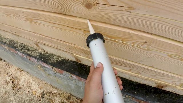 Warming of a wooden house from a bar, painting and sealing during the summer per