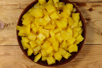 Diced pineapple in a plate on wooden table. Top view