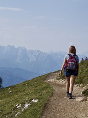 Obraz premium Ein junge Frau wandert auf einem steinigen Weg zu einer Alm
