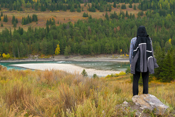 tourist, a man in a sports jacket on the mountain look at the autumn landscape with forest and...
