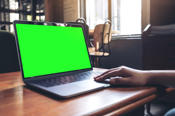 Mockup image of hand using and typing at laptop with blank desktop screen on wooden table in cafe