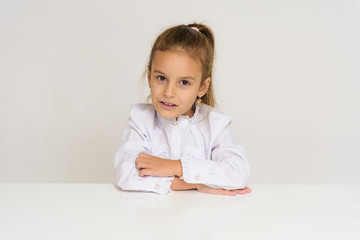 Portrait of a cute baby girl on a white background at the table.