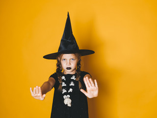 young halloween witch on orange background with black hat