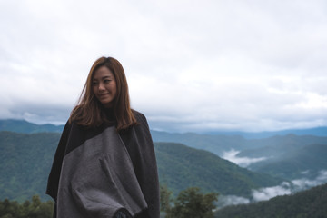 A woman standing alone and looking at mountains on foggy day with blue sky background in the morning