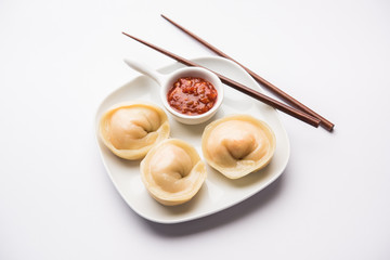 Dumpling momos food from Nepal or Ladakh served with red chilli chutney over moody background. Selective focus