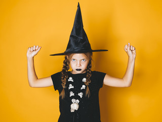young halloween witch on orange background with black hat