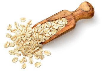 raw oatmeal in the wooden scoop, isolated on white, top view