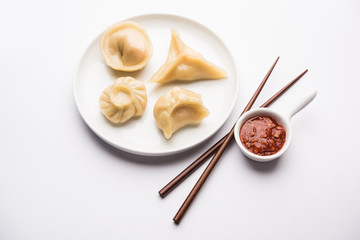 Dumpling momos food from Nepal or Ladakh served with red chilli chutney over moody background. Selective focus