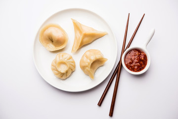 Dumpling momos food from Nepal or Ladakh served with red chilli chutney over moody background....