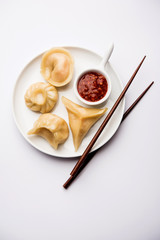 Dumpling momos food from Nepal or Ladakh served with red chilli chutney over moody background. Selective focus