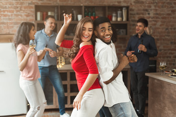 Happy interracial couple dancing at home party