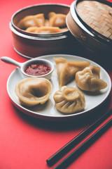 Dumpling momos food from Nepal or Ladakh served with red chilli chutney over moody background. Selective focus