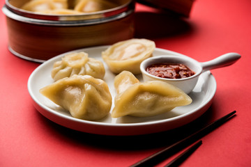 Dumpling momos food from Nepal or Ladakh served with red chilli chutney over moody background. Selective focus
