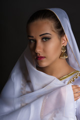 Close up portrait of beautiful Caucasus young woman wearing traditional costume. Studio shot over black background