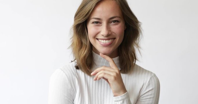 Young brunette woman on white background considering and smiles  to the camera closeup