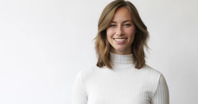 Young brunette woman on white background smiles and laughs to the camera