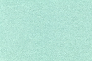 Texture of old light cyan paper background, closeup. Structure of dense turquoise cardboard