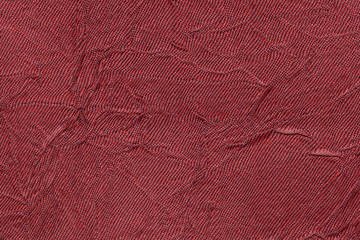 Dark red wavy background from a textile material. Fabric with fold texture closeup.