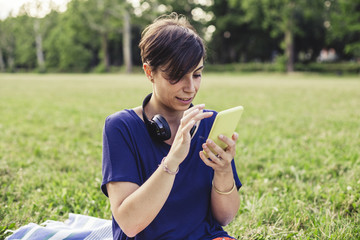 Young adult woman using a mobile phone at the public park in summer