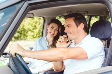 happy adult couple travelling by car while man talking by phone