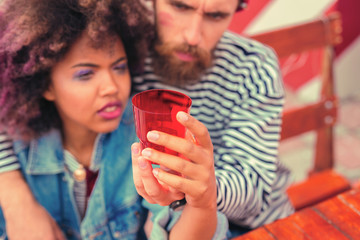 Red glass. Tired young people sitting together and thoughtfully looking at the red glass after tiresome night party