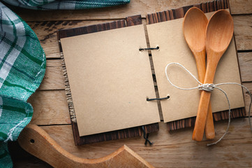 Blank vintage recipe cookbook and utensils on wooden background, top view, copy space