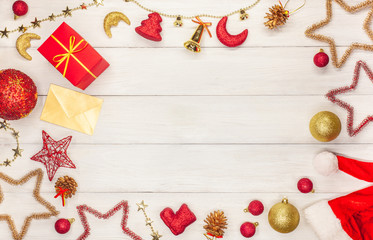 Christmas star toys, balls, bells, Christmas bells, asterisks, a box with a gift and a gold envelope on a white wooden table