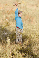 cute little kid in field playing with toy airplane in field