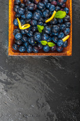 Fresh and raw blueberries. On black background with texture and streaks. Space to insert your text.