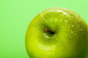 Green Apple With Water Drops On Green Background Close-up