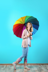 Woman with rainbow umbrella near color wall