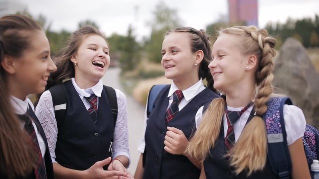 Schoolgirls having fun after school on the street. Girl student wearing the same school uniform laughing and singing after school in the Park.