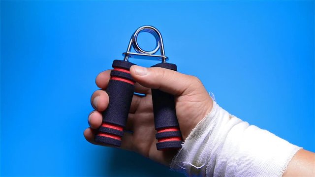 hurt hand doing rehabilitation exercises by squeezing an A shape hand trainer